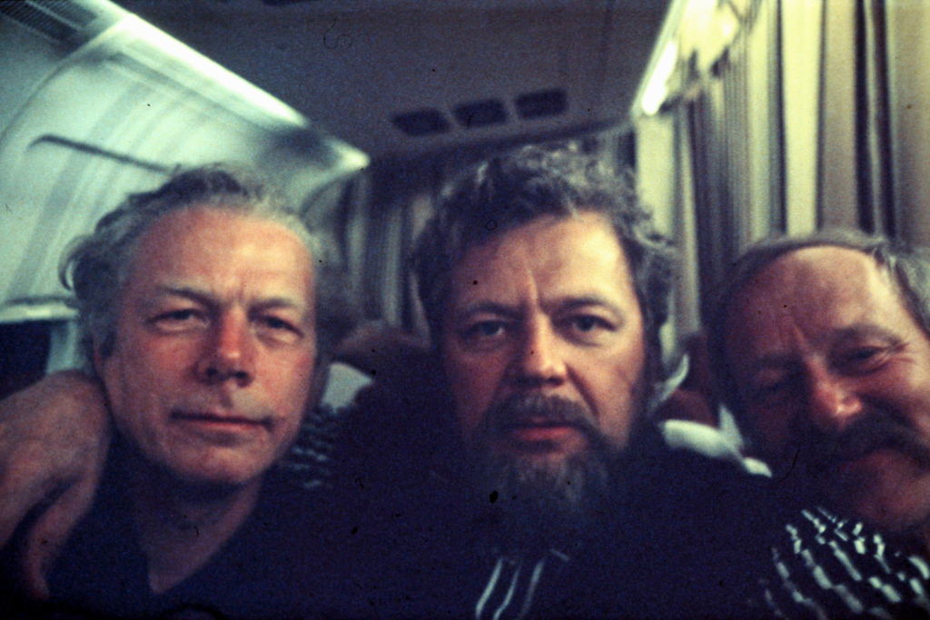 Kolme miestä kaulailee.