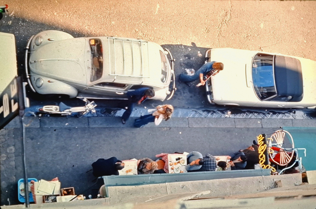 Katunäkymä ylhäältä päin, ihmisiä ja autoja.