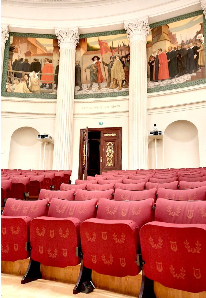 Helsingin yliopiston juhlasalin tuoleja ja seinien maalauksia.