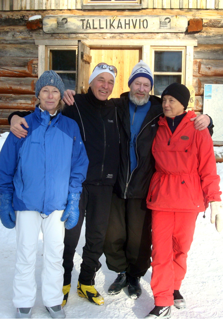 Neljä ihmistä hiihtoasuissa latukahvion edessä.