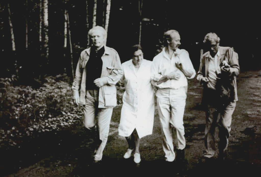 Neljä ihmistä rinnakkain hiekkatiellä.